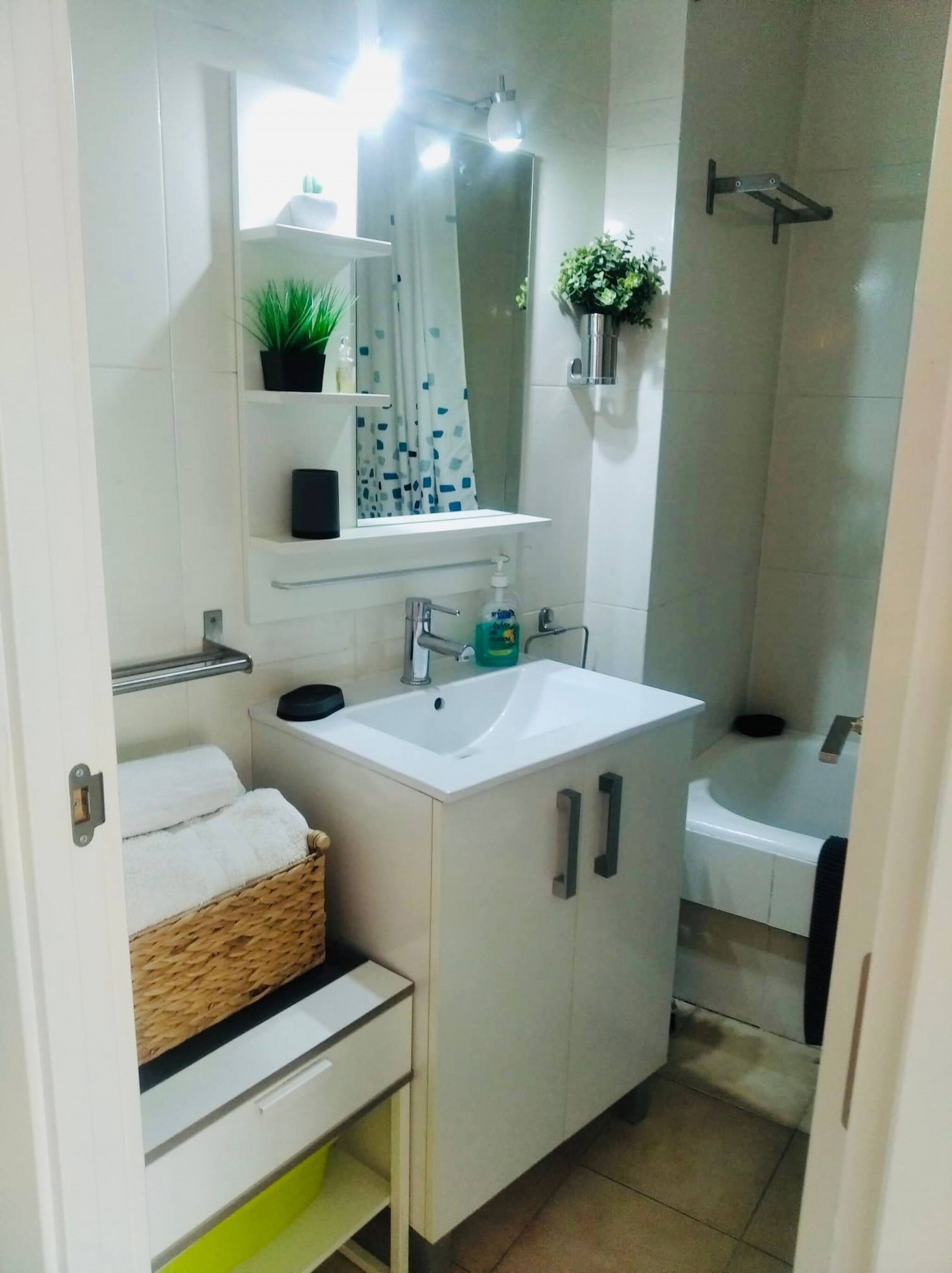 Een badkamer met een wit wastafelmeubel, spiegel en een douchehoek.