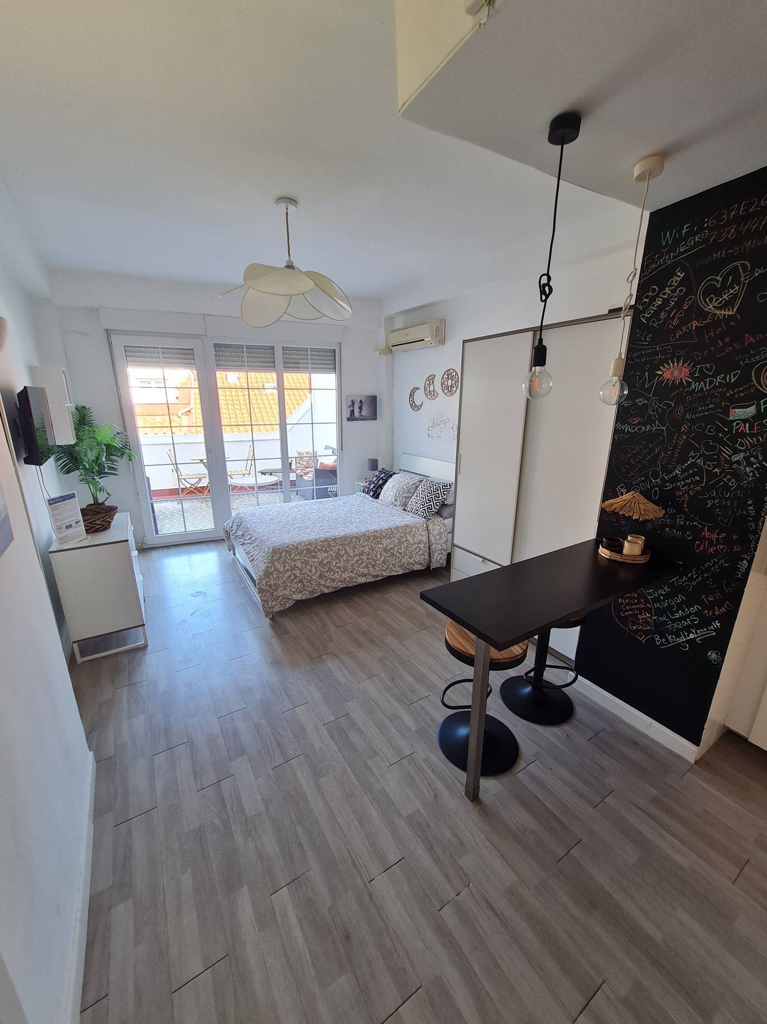 Une chambre moderne avec un lit, un bureau et un mur recouvert d’un tableau noir sur lequel on a écrit.