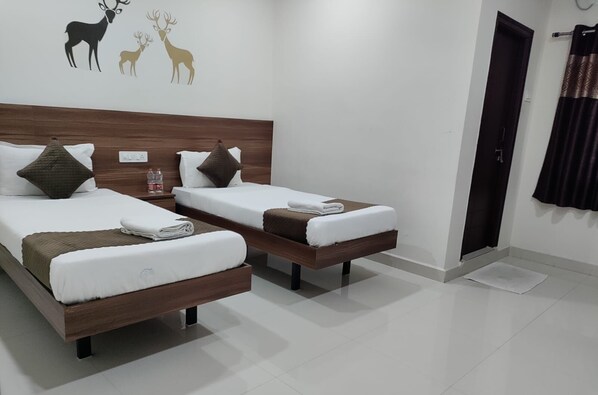 Habitación de hotel con dos camas individuales, cabecero de madera, pared decorada con un ciervo y una puerta con cortina.