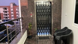 Een balkon met een metalen hekwerk, bloempotten en buitenmeubilair.