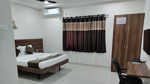 Een hotelkamer met een bed, een bureau, een stoel, een kledingkast en een airconditioner.