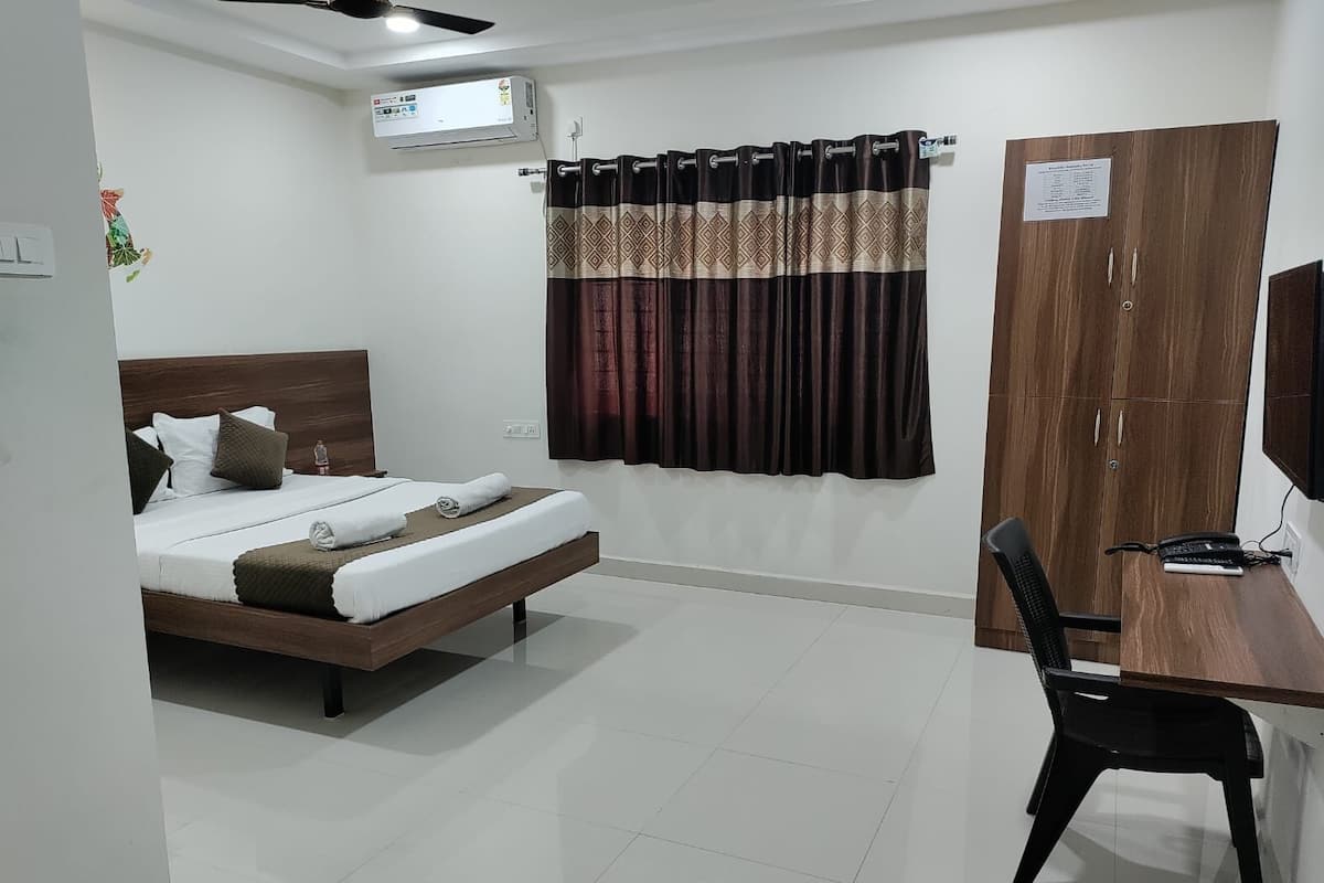 Une chambre d’hôtel équipée d’un lit, d’un bureau, d’une chaise, d’une armoire et d’un appareil de climatisation.