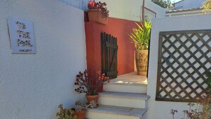 A set of stone steps leading to a door, surrounded by potted plants and decorative items.