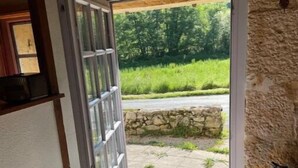 Ein Durchgang zu einem von Steinplatten ausgelegten Bereich mit Blick auf Grünflächen und eine Straße.