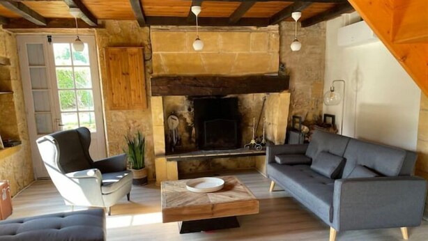 Ein gemütliches Wohnzimmer mit Kamin, Holzbalken und einem modernen Sofa.