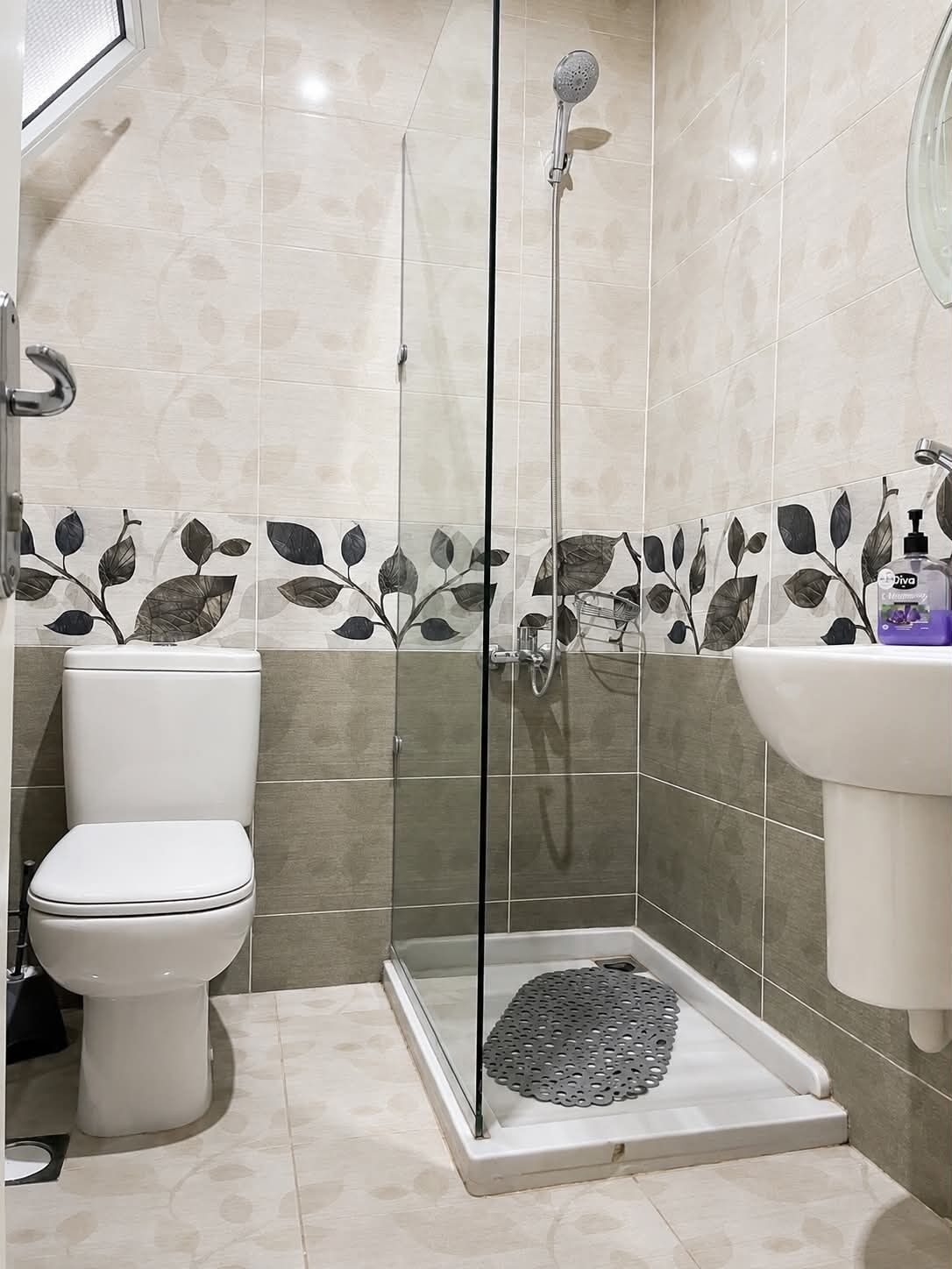A bathroom with a toilet, a shower enclosure, and a sink.