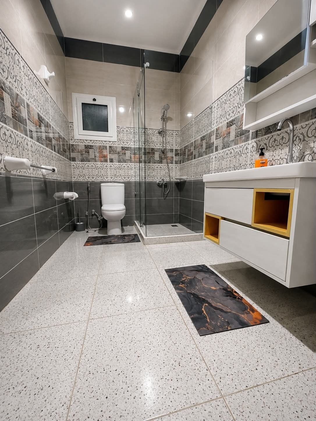 A modern bathroom with a toilet, shower, and vanity.