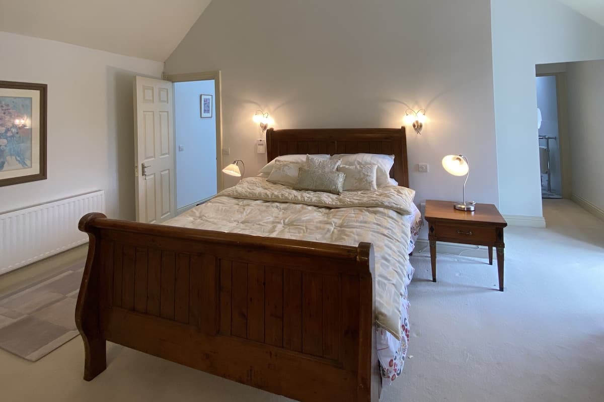 A bedroom with a wooden bed, a ceiling light fixture, and a nightstand with a lamp.