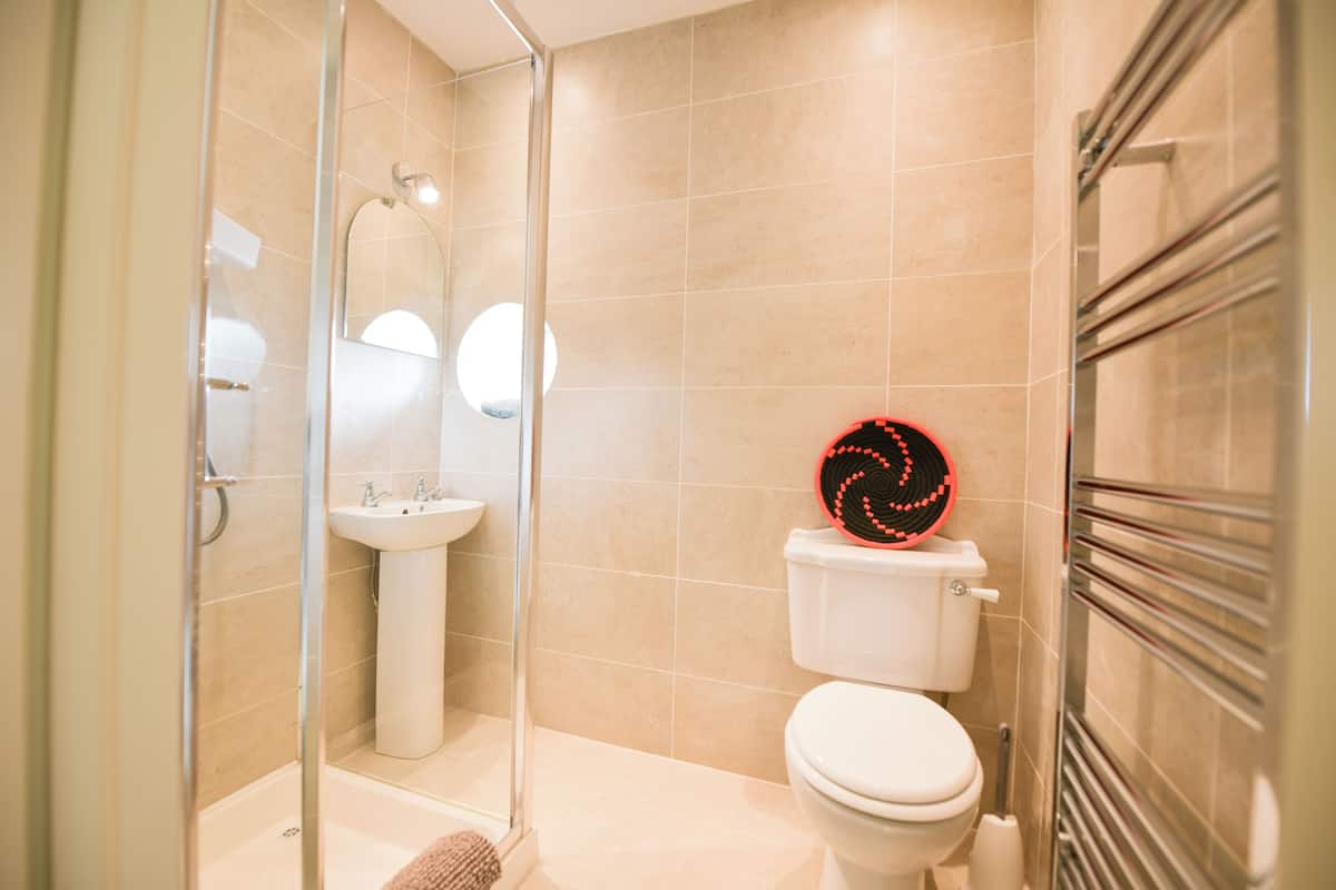 A bathroom with a glass-enclosed shower, a sink, a toilet, and a towel rack.
