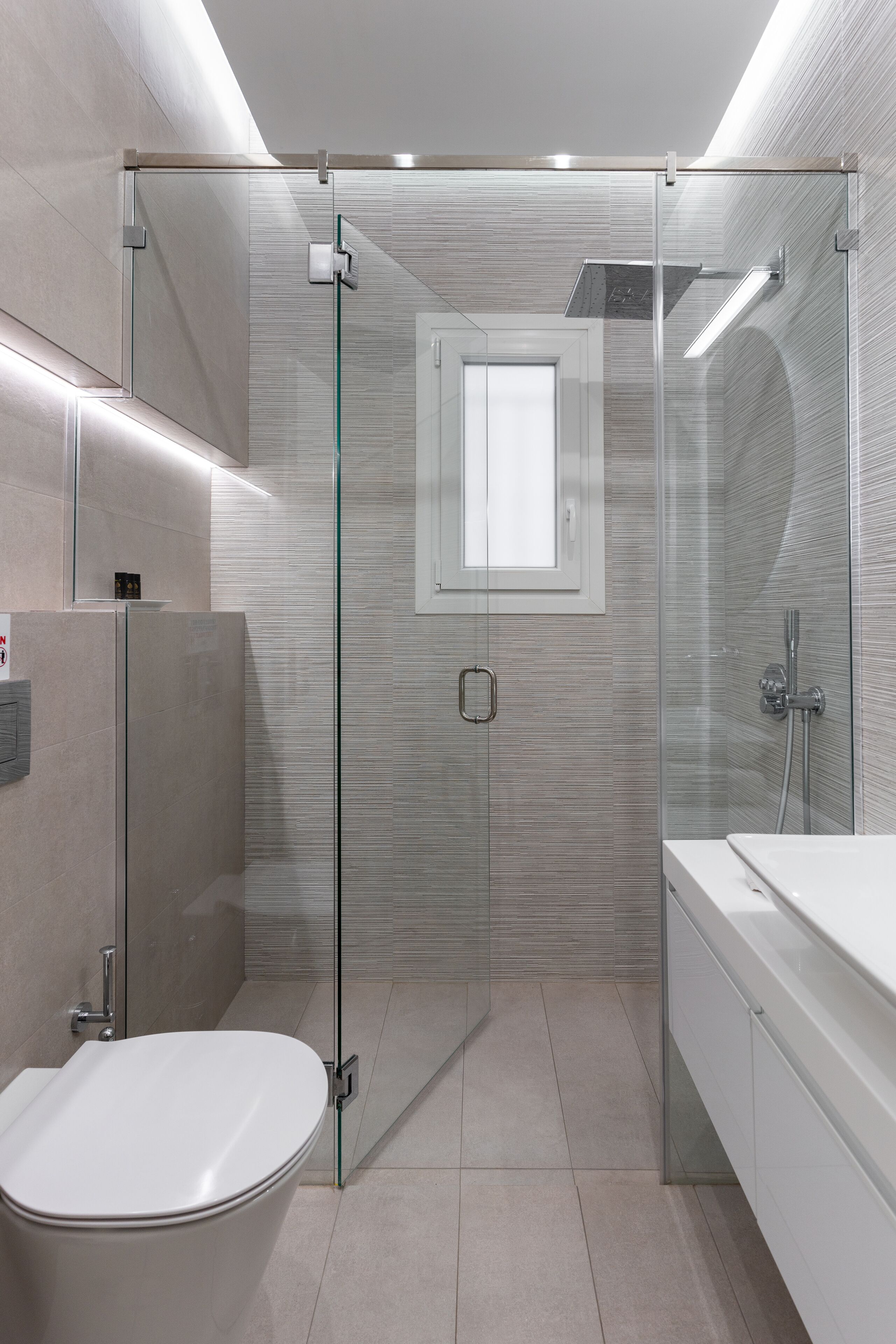 Een moderne badkamer met een douchecabine van glas, een toilet en een wastafel.