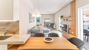 Een moderne keuken met een centraal eiland, een eetgedeelte met een houten tafel en een woonruimte met een bank en stoelen.