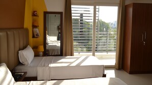 A hotel room with a bed, a nightstand, a mirror, a wardrobe, and a large window with curtains. - Covie Gurgaon 108 (Gurugram)