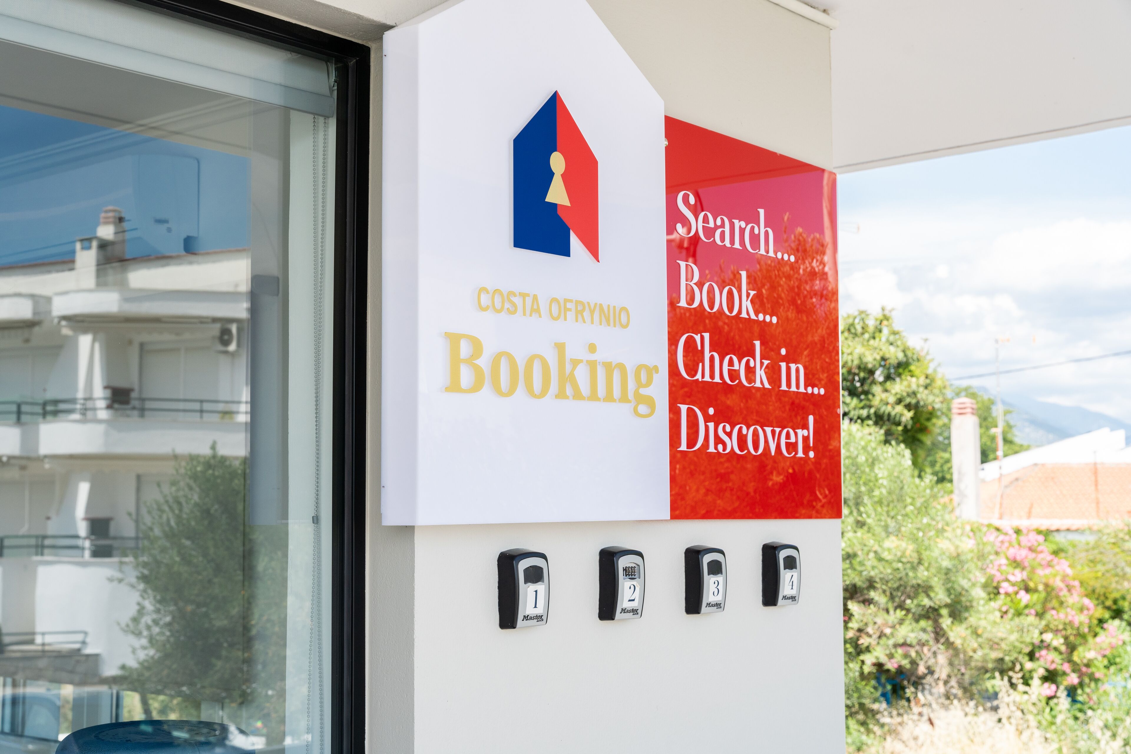Cartell de Costa Ofrynio Booking amb un logotip, una casella de recerca, botons per reservar, fer el check-in i descobrir, i tres teclats numèrics.