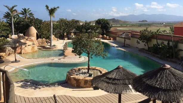 A resort pool area with a clear view of the surrounding landscape, including mountains and palm trees.