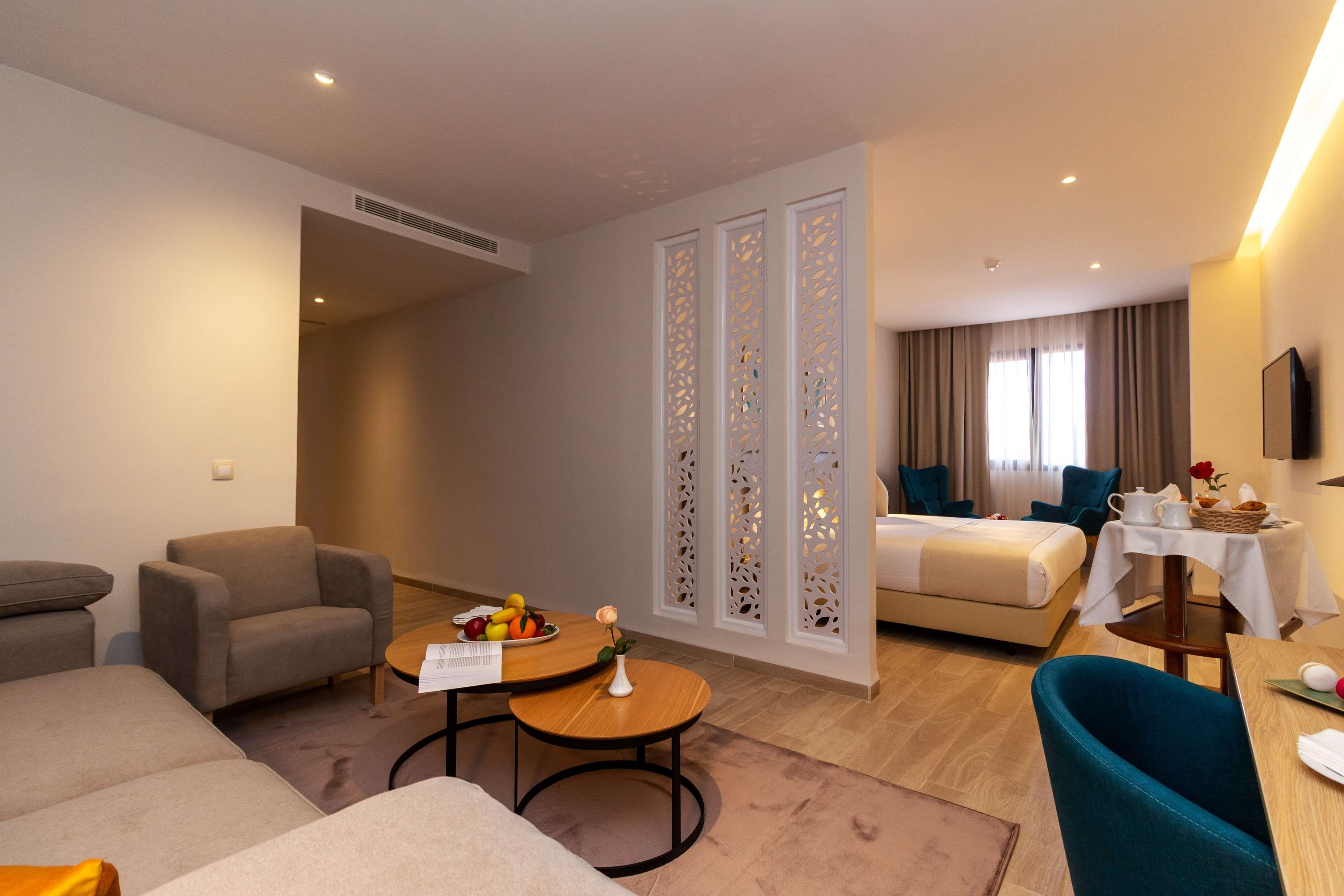 Una habitación de hotel con sofá, sillón, mesa de comedor y cama.