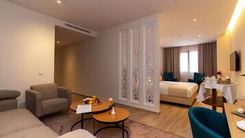 Una habitación de hotel con sofá, sillón, mesa de comedor y cama.