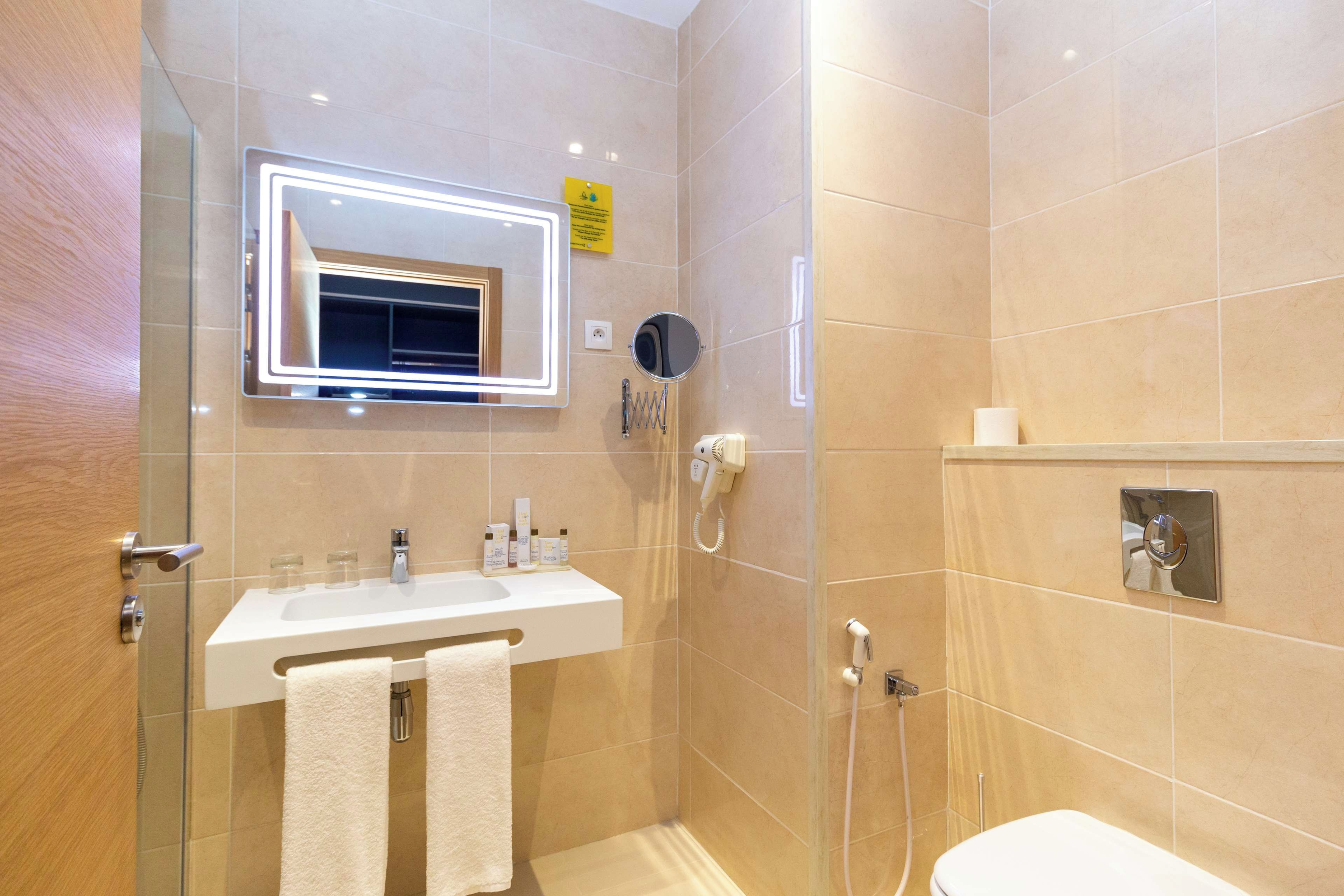 Un baño moderno con cabina de ducha de vidrio, tocador con espejo y un inodoro.