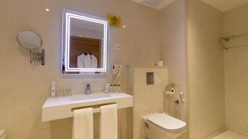 Un baño moderno con tocador, espejo con luces, inodoro y zona de ducha.