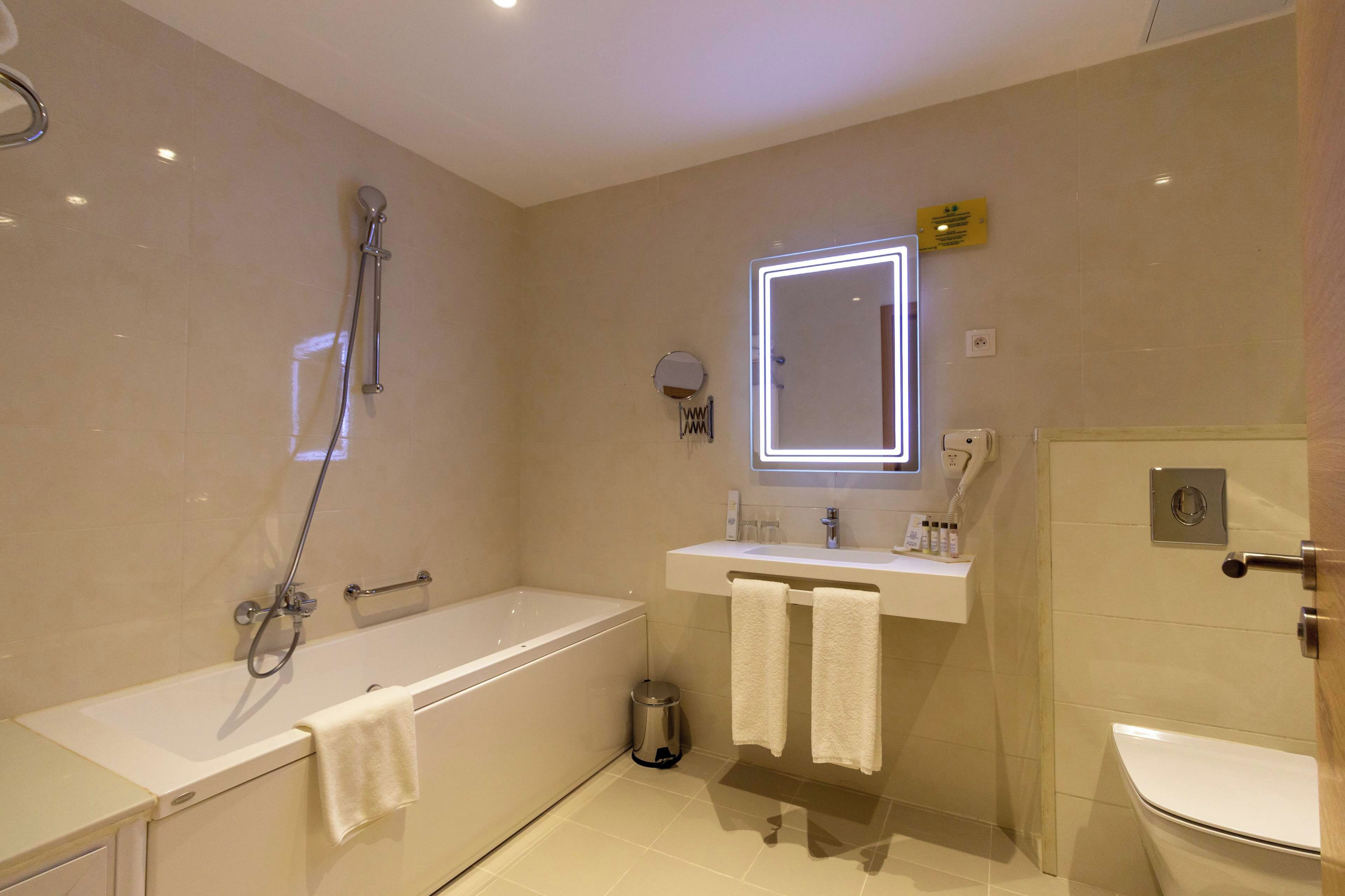 Un baño moderno con bañera, lavamanos con espejo y un inodoro.