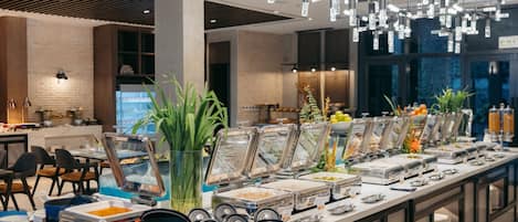 Montaje de bufé con varios recipientes de comida y una decoración interior moderna.