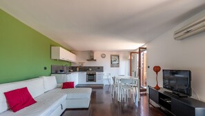 Een moderne woonkamer met een bank, een eethoek en een keuken op de achtergrond.