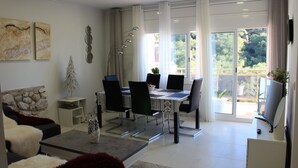 Ein modernes Wohnzimmer mit Essbereich, einer Wand aus Stein und einer großen Schiebetür, die auf einen Balkon führt.