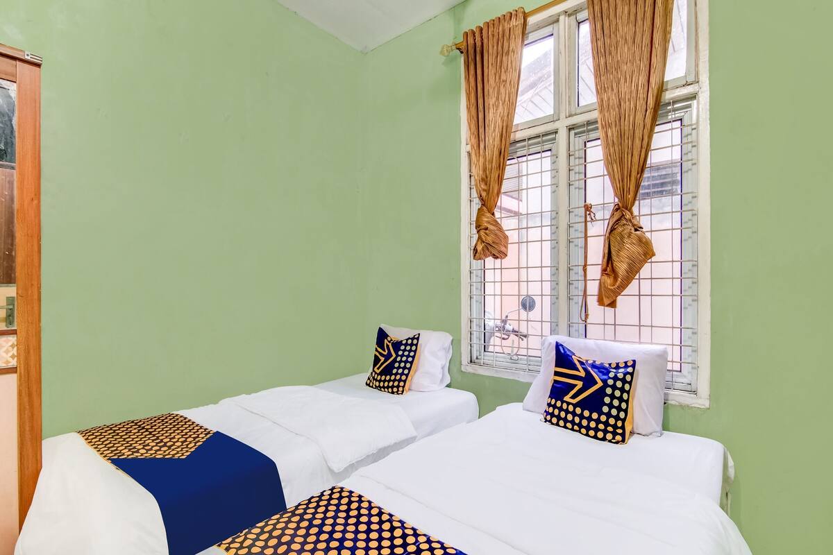 Ein Zimmer mit zwei Betten, jeweils mit weißer und blauer Bettdecke sowie passenden Kissen mit blau-gelben Mustern.