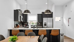 Une cuisine moderne avec des meubles de couleur sombre, des appareils en acier inoxydable et un îlot central doté de sièges.