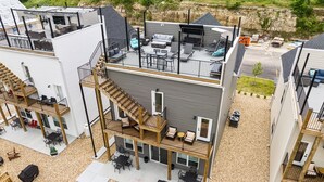 Un immeuble à plusieurs étages doté d’espaces extérieurs aménagés pour s’asseoir, d’une terrasse couverte et d’un escalier menant à l’étage supérieur.