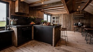 Een landelijke keuken met houten balken, een zwart aanrecht en een groot raam.