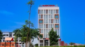 A multi-story hotel with a prominent 'MARCHICA' sign, a red-roofed structure to the left, and a well-maintained lawn in front. - Marchica Hotel (Nador)