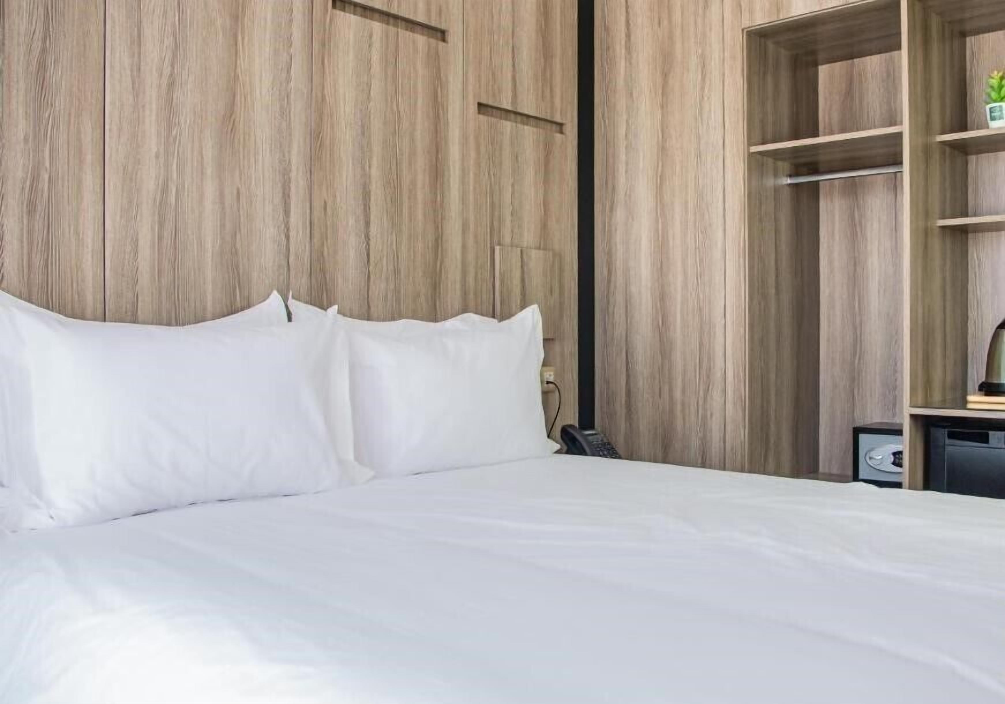 Ein Bett mit weißer Bettwäsche, ein Holzschrank und ein kleiner Schreibtisch mit Lampe.
