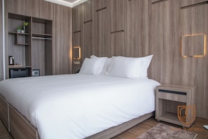 Un dormitorio moderno con una cama grande, paredes de paneles de madera, una mesita de noche y una pequeña estantería con objetos decorativos.