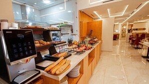 A breakfast buffet with a Nescafe coffee machine, various breads, pastries, and fruits. - Marchica Hotel (Nador)