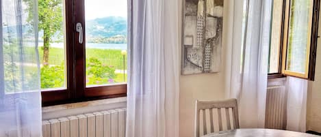 A room with a view of a lake and mountains, a radiator, a table, and a chair.