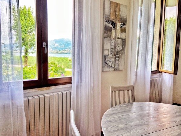 Una habitación con vistas a un lago y montañas, un radiador, una mesa y una silla.