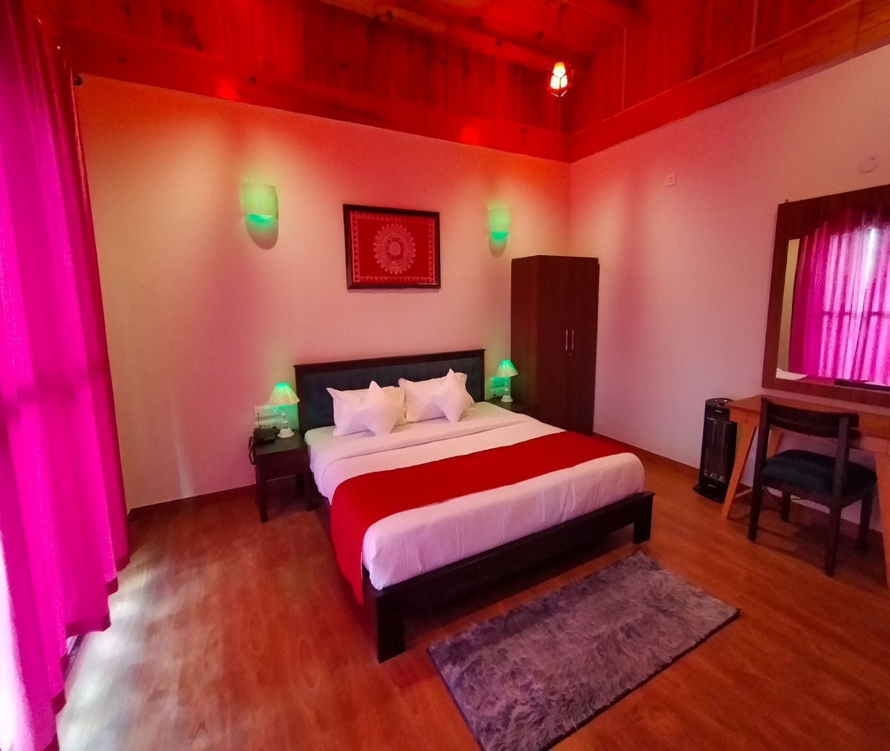 A bedroom with a bed, nightstands, a desk, a chair, a wardrobe, and a red and white bedspread.
