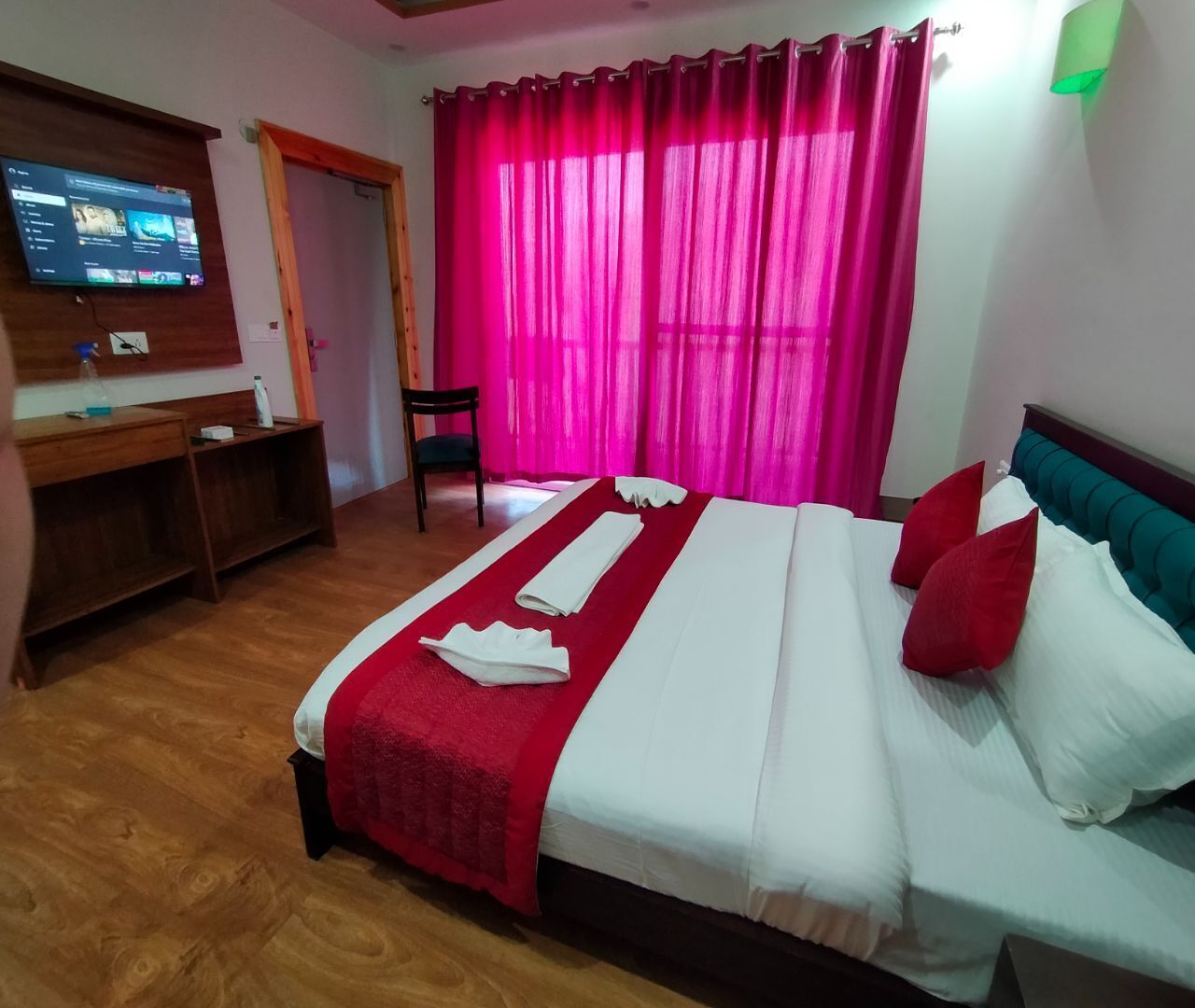 A hotel room with a bed, a desk, and a television.