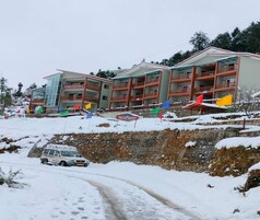 A multi-story hotel with balconies, a stone retaining wall, and a snow-covered landscape.
