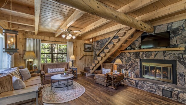 A cozy log cabin interior with a stone fireplace, wooden beams, and a comfortable seating area. - Three-Story Home -1/8 of a mile of Fishing the Rio Grande River (Creede)
