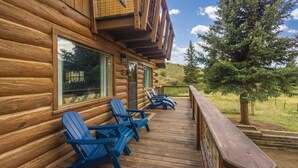 A log cabin with a wooden deck, outdoor seating, and a view of the surrounding landscape. - Three-Story Home -1/8 of a mile of Fishing the Rio Grande River (Creede)