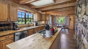 A spacious kitchen with wooden cabinets, a large island, and a view of the outdoors. - Three-Story Home -1/8 of a mile of Fishing the Rio Grande River (Creede)