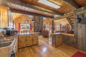 L’intérieur d’un chalet rustique, avec un revêtement mural en bois, une grande cuisine et un espace repas.
