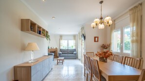 A spacious kitchen with a dining area, a sofa, and a TV mounted on the wall. - Mercedes: Beautiful detached house with a large garden (L'Escala)