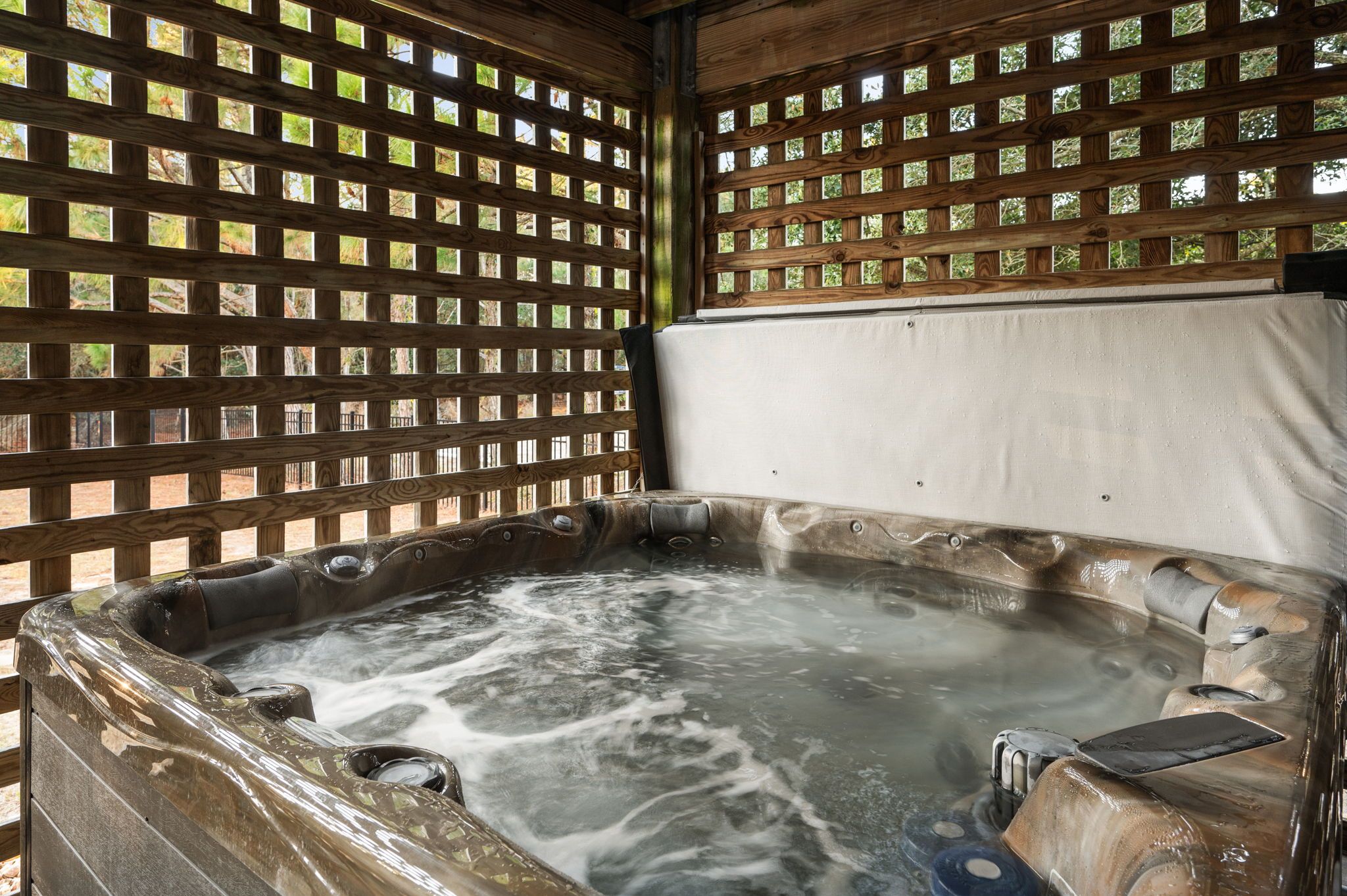 A hot tub with a wooden lattice backdrop.