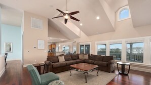 A spacious living room with a large sectional sofa, a coffee table, and a ceiling fan.