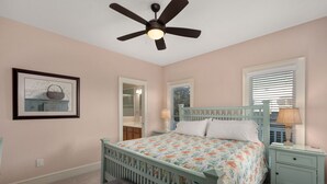 A bedroom with a bed, a nightstand, a dresser, a ceiling fan, a window with blinds, and a framed picture on the wall.