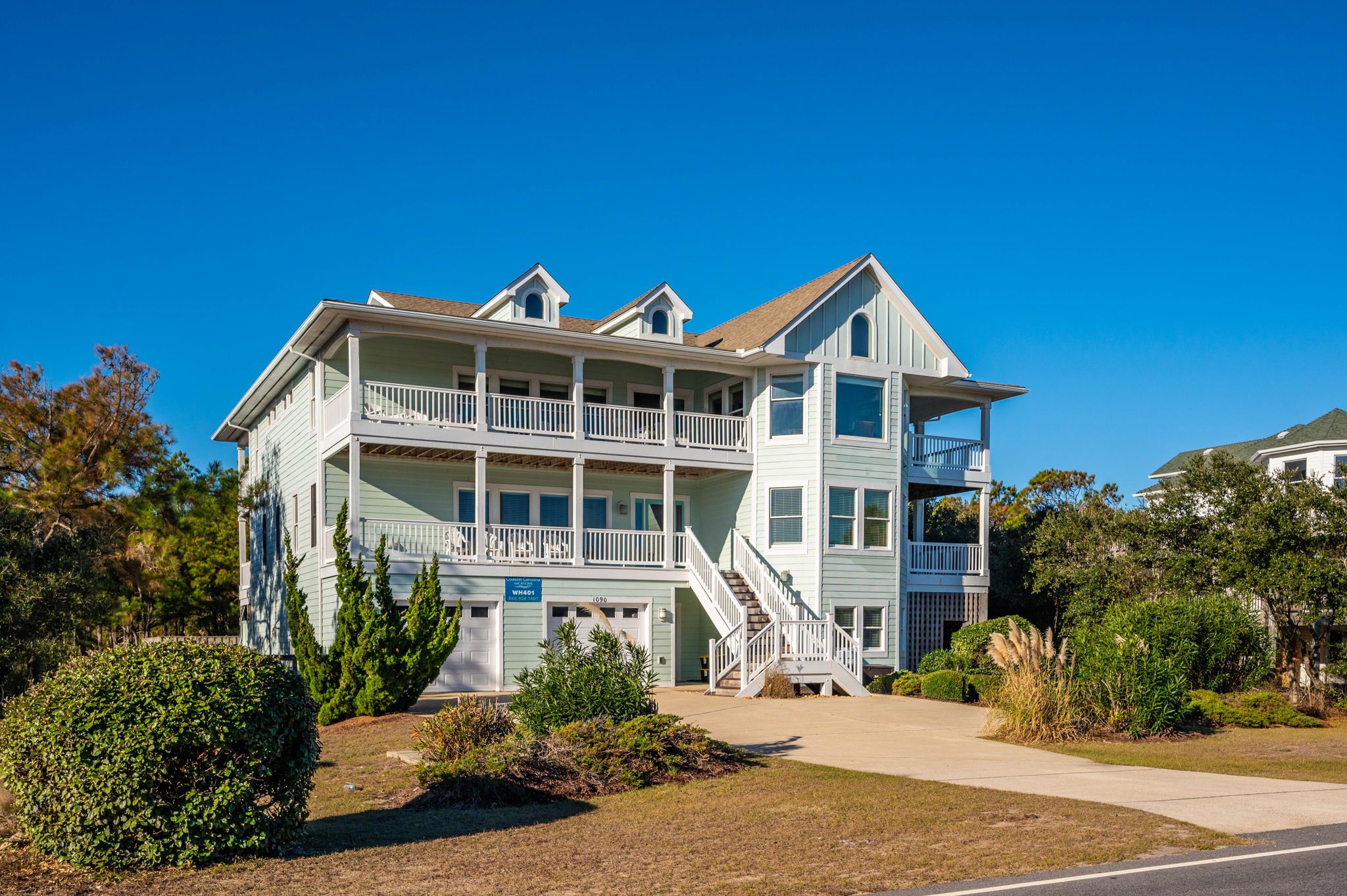A two-story building with a balcony on the second floor, a staircase leading to the second floor, and a garage with a sign indicating the address.
