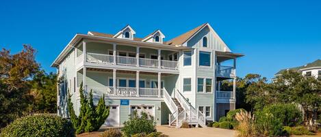 A two-story building with a balcony on the second floor, a staircase leading to the second floor, and a garage with a sign indicating the address.