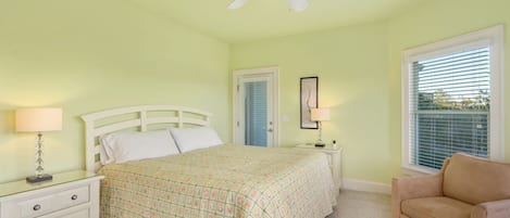 A bedroom with a bed, nightstands, a chair, a ceiling fan, and a window with blinds.